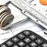 Coins scattered on a budget report with a stack of coins in the center.