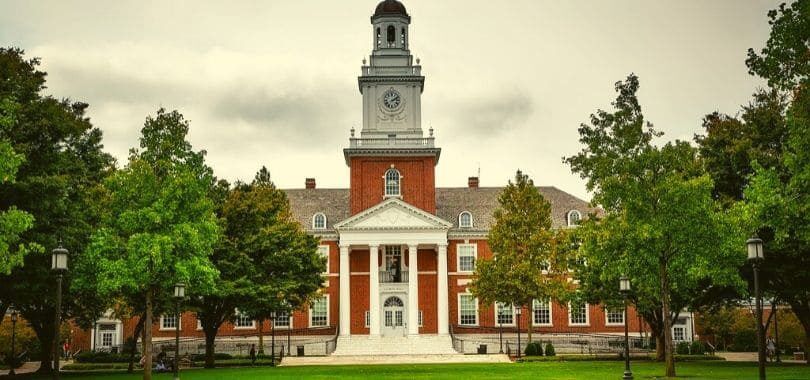 A shot of a Johns Hopkins University building with trees in front of it.