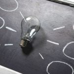 A chalkboard with a light bulb in the center, with lines and circles around it.