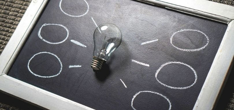A chalkboard with a light bulb in the center, with lines and circles around it.