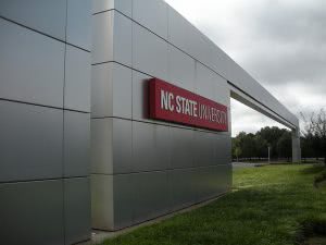 Red NC State University name sign on the outside of a silver building