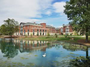 Elon University building with a swan in the lake foreground.