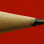 Sharp pencil head closeup on red background.