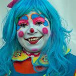 Portrait of a smiling and colorful girl clown.