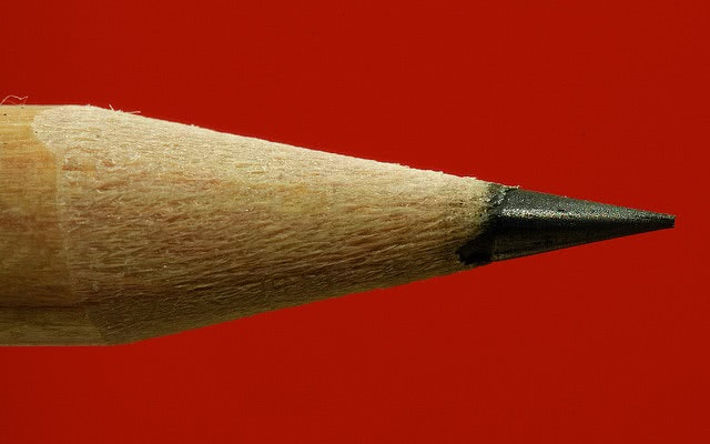 Sharp pencil head closeup on red background.