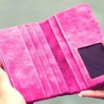 A person holding an empty pink wallet.