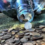 Coins are spilling from a glass jar.