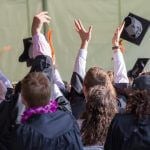 Graduating college students tossing their caps into the air.