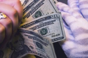 Portrait of a hand holding 4 twenty dollar paper bills.