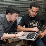 Two male students looking at the laptop.