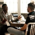 Two students talking to each other at a table.