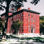 A red-bricked building on a college campus with students walking around.