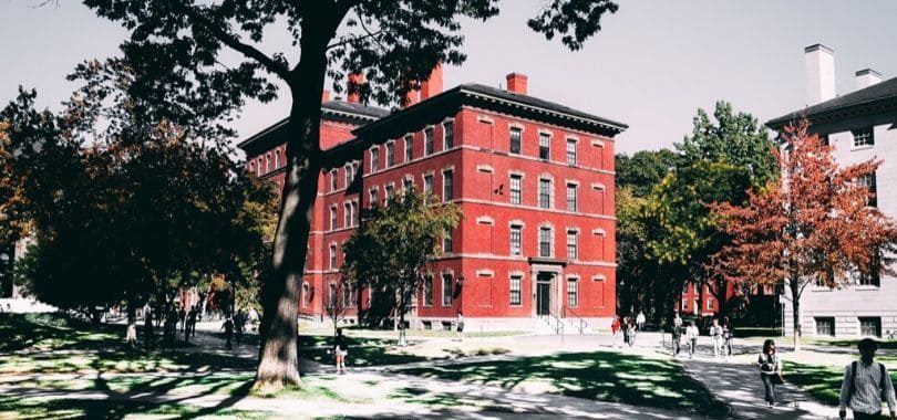 A red-bricked building on a college campus with students walking around.