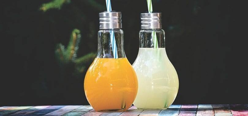 Two light bulbs filled with drinks, with straws in them.