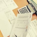 A desk covered in papers with a calculator.