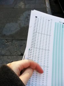 A student's hand holding a multiple choice answer sheet.