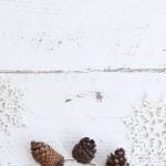 Pine cones and snowflakes on a wooden counter.