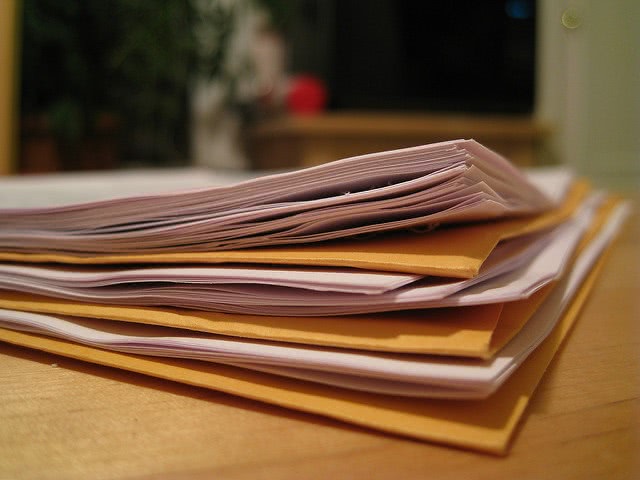 A pile of papers and manila folders on a desk.