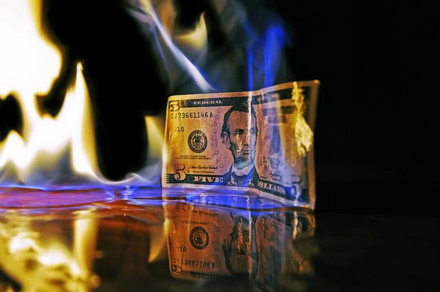 Five dollar bill burning with fire.