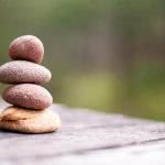 Four rocks stacked on top of each other on a table outside.