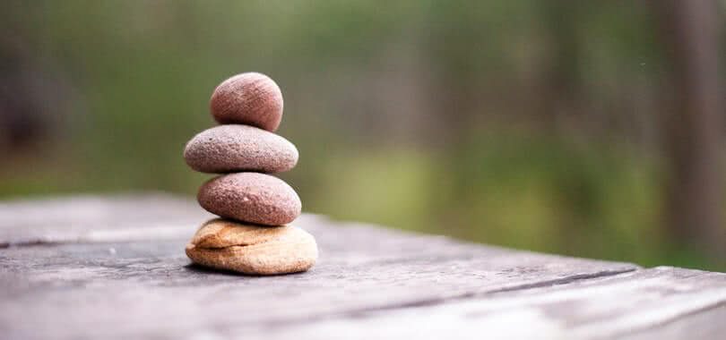 Four rocks stacked on top of each other on a table outside.