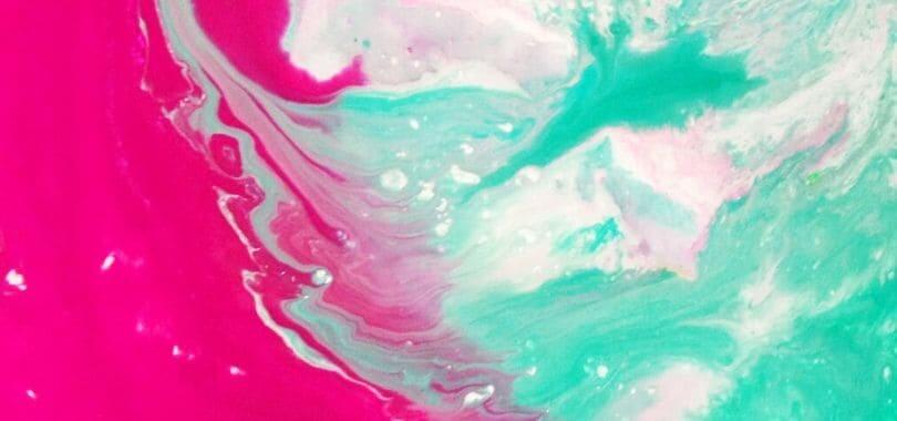 Teal, white, and magenta paint mixing together.