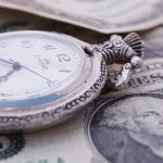 A stopwatch sitting on top of money.