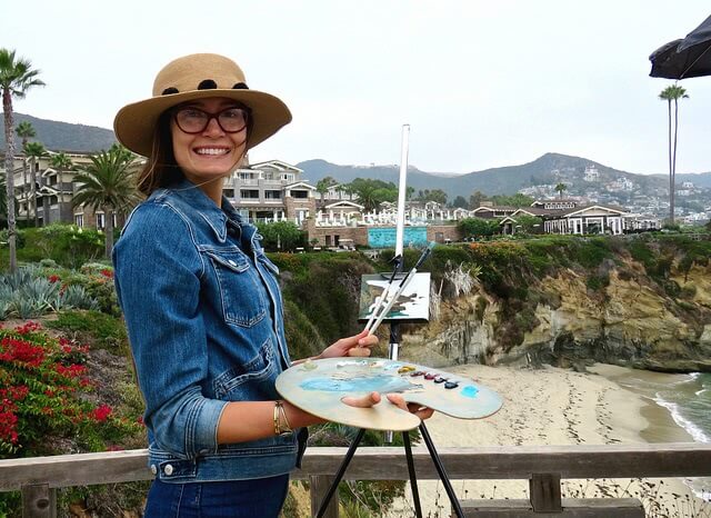 Girl holding a paintbrush and plate while standing at Montage Resort in the background.