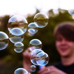 A young boy blurred in the background blowing bubbles.