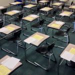 Classroom chairs with test papers on the desk.