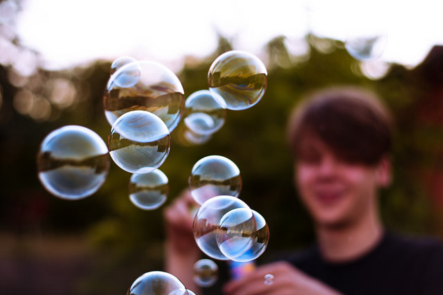 A young boy blurred in the background blowing bubbles.