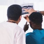 Three dentists looking at an x-ray of someone's teeth.