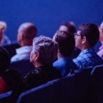 A group of people sitting in dark auditorium.