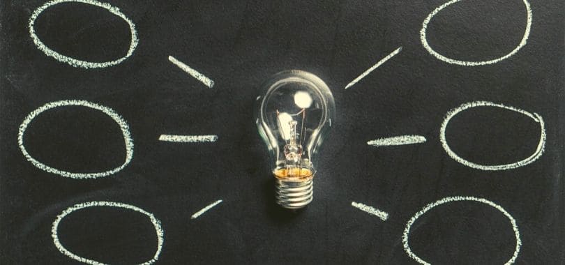 A light bulb on a chalkboard, with chalk circles around it.