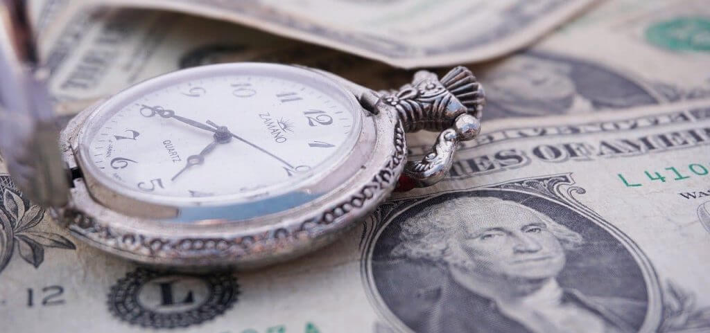 A stopwatch sitting on top of money.