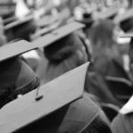 Students wearing graduation robes and caps standing together.