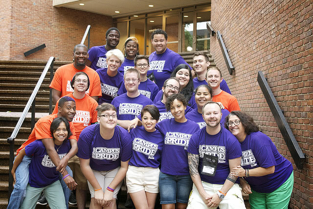 Smiling alumni wearing violet and orange shirts that say "Campus Pride".