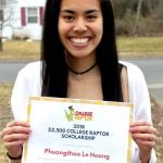 A young female student smiling while holding a $2500 College Raptor Scholarship certificate.