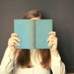 A person holding an open book in front of their face.