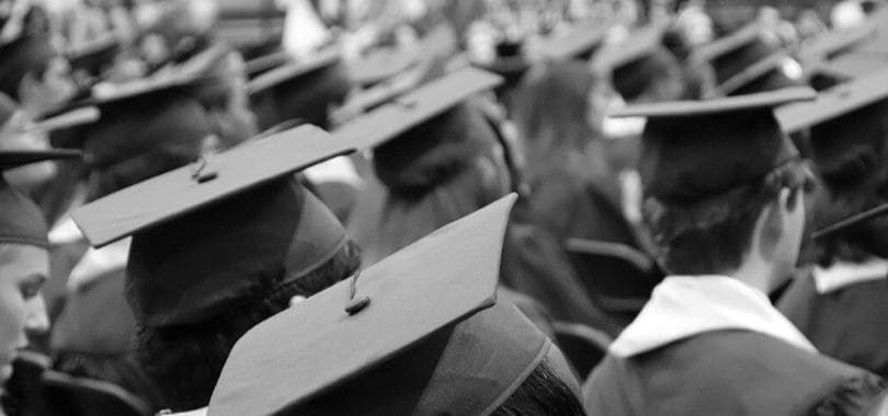 Students wearing graduation robes and caps standing together.