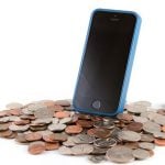 A smartphone is standing on a pile of coins.