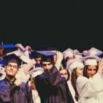 Students graduating, wearing robes and moving their tassels.