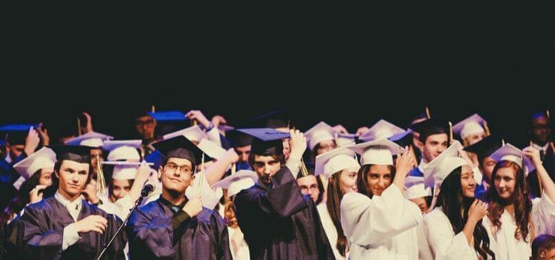 Students graduating, wearing robes and moving their tassels.