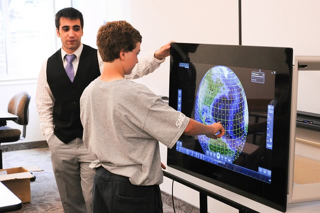 Student pointing his finger to the monitor with his professor beside him.