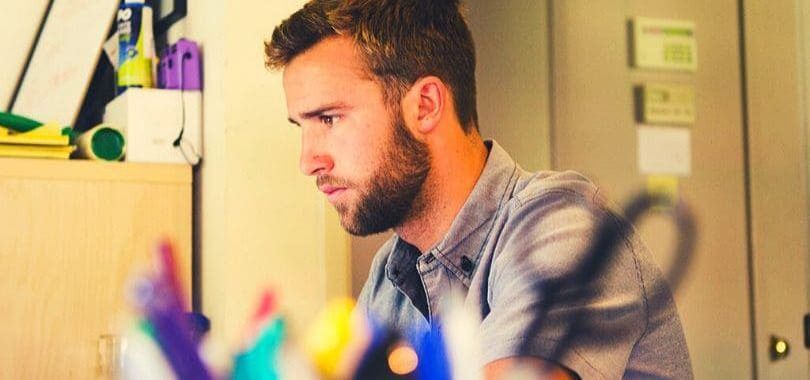 A student sitting at a desk with office supplies in the foreground.