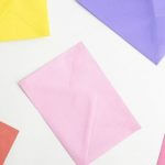 Various colorful envelopes scattered on a white surface.