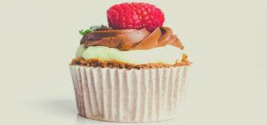 A chocolate cupcake with a raspberry on top. 