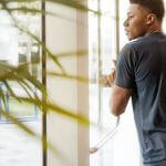 Student pushing open a door, with a plant in the foreground.