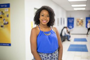 Image of a smiling black woman standing in the hallway.