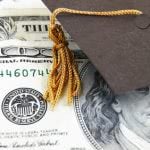 Graduation cap tassel covering the upper right side of one hundred dollar bill.